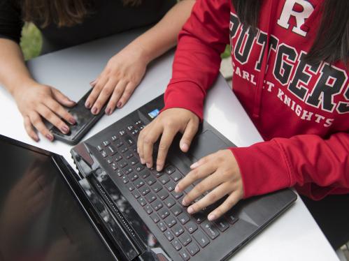 A person's hands rest on a laptop keyboard